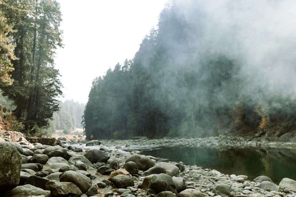 Stony shore and a shallow river crossing in morning mist.